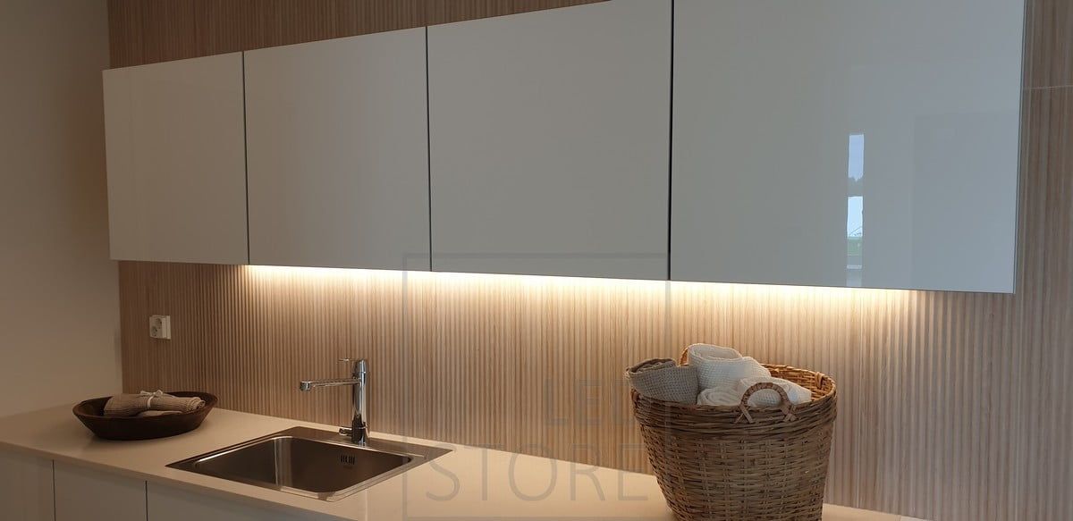Above the worktop, at the bottom of the cupboards, a LED strip in a low profile surface illuminates the space between the utility room and the living room
